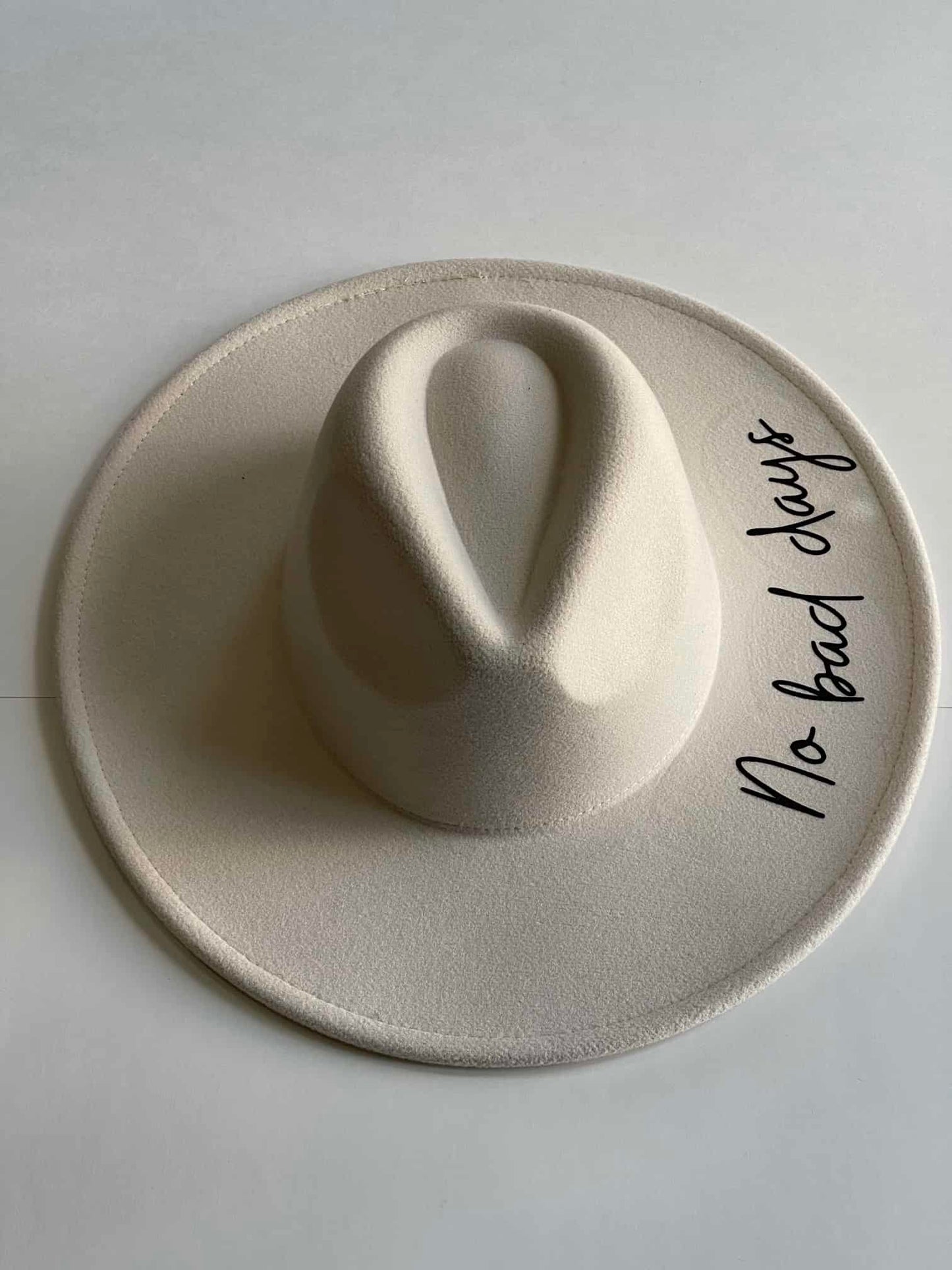 ¡Añade un toque de positivismo a tu look con este hermoso sombrero Fedora blanco con la frase "No bad days" en uno de los lados! 