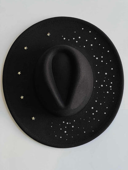 ¡Añade un toque de elegancia y originalidad a tu outfit con Estrella Negra, el sombrero fedora con detalles plateados! Este sombrero es imprescindible para cualquier amante de la moda que busca un toque de sofisticación en su look.