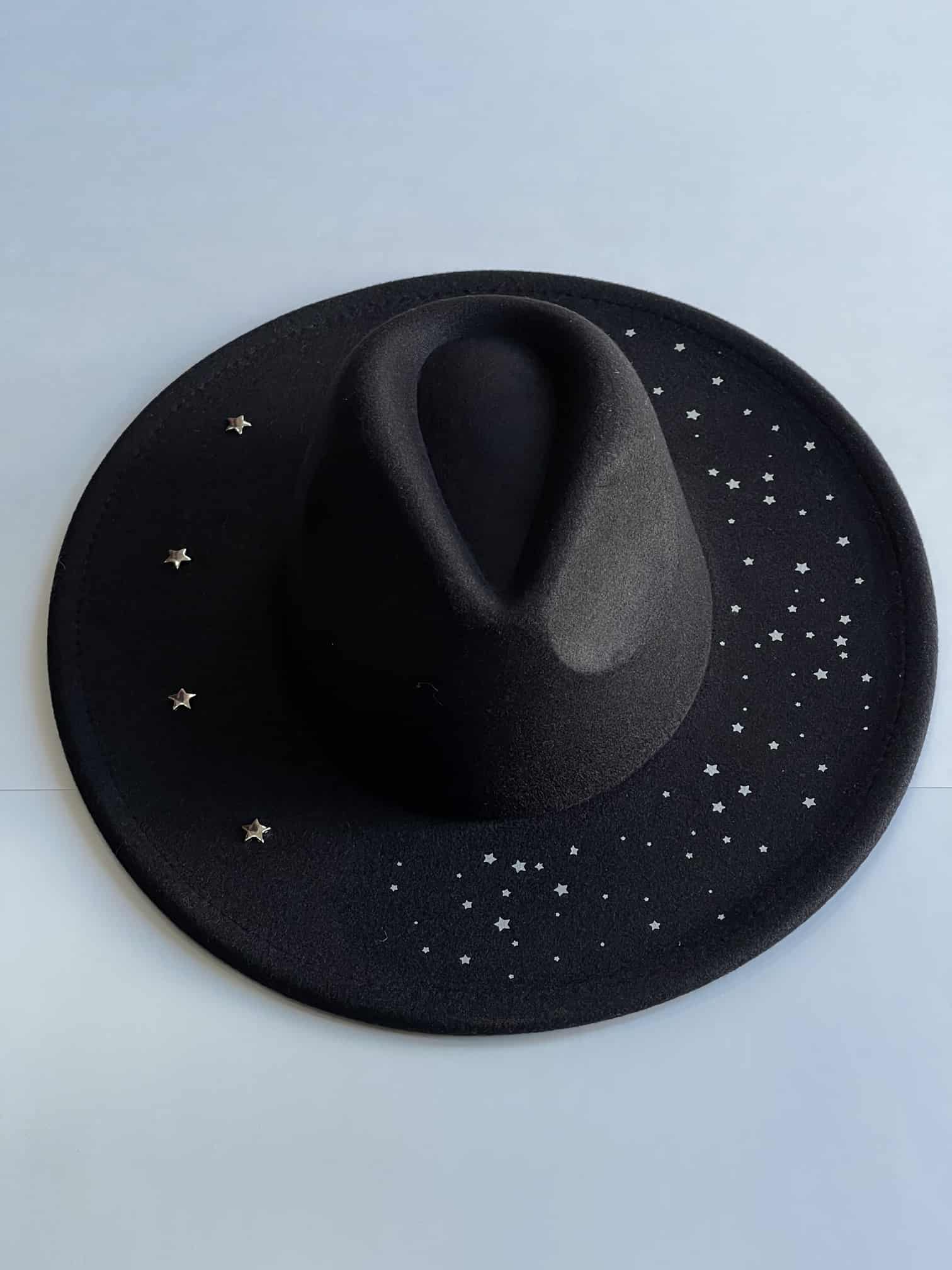 ¡Añade un toque de elegancia y originalidad a tu outfit con Estrella Negra, el sombrero fedora con detalles plateados! Este sombrero es imprescindible para cualquier amante de la moda que busca un toque de sofisticación en su look.